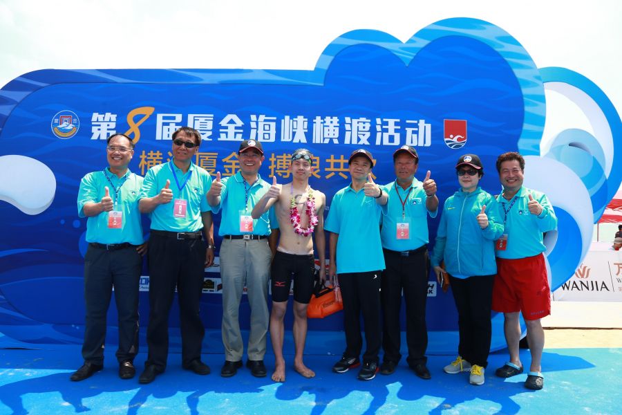 在2016年第八屆金廈泳渡首次奪冠的台灣選手卓承齊與金門縣副縣長吳成典（左3）等人合影留念。主辦單位提供