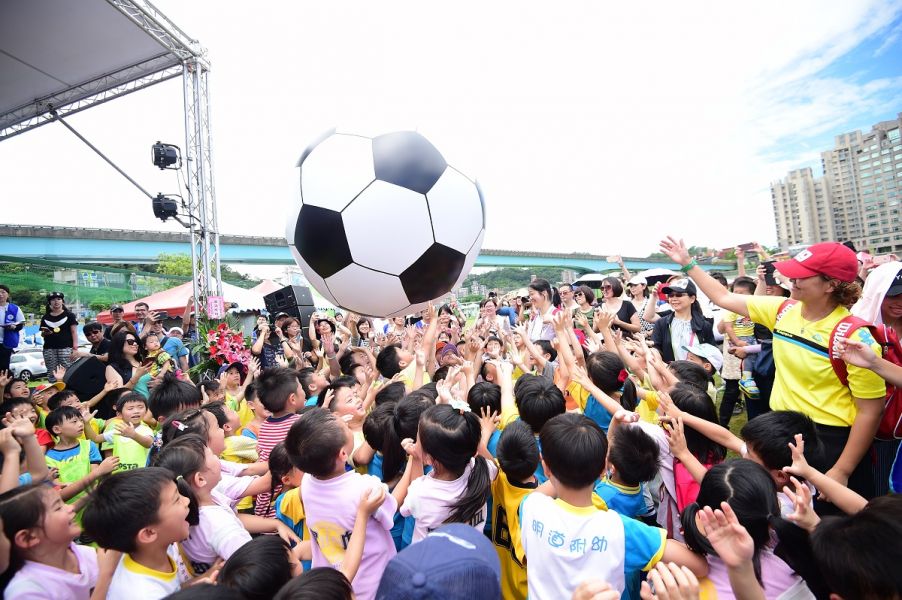 足球小將們高舉雙手滾動巨型足球，象徵著小朋友在場上團結滾動足球的熱情和齊心合力將球踢進球門的精神。(主辦單位提供)