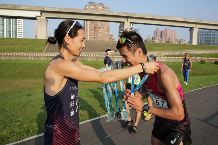 奧運馬拉松選手張嘉哲為完賽跑友掛牌暖心服務。