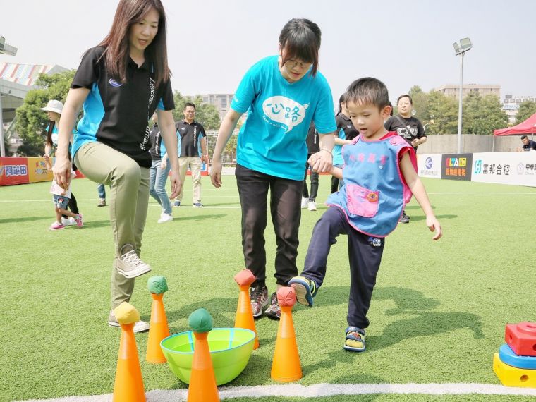 心路基金會的小朋友在志工陪伴下體驗足球活動的樂趣。大會提供