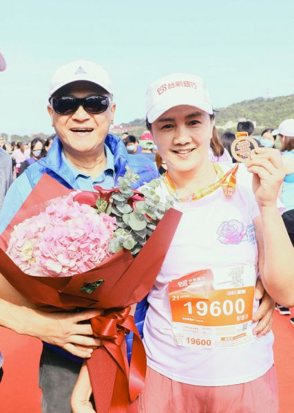台新金控董事長吳東亮在終點獻上鮮花，熱情迎接成功征服21公里的夫人彭雪芬。路跑協會提供