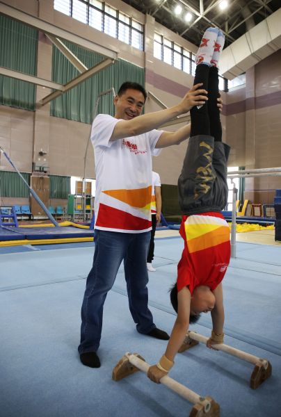 華南銀行副董事長林知延藉著華南銀行第二屆小小體操營的課程中，細心保護小選手。主辦單位提供