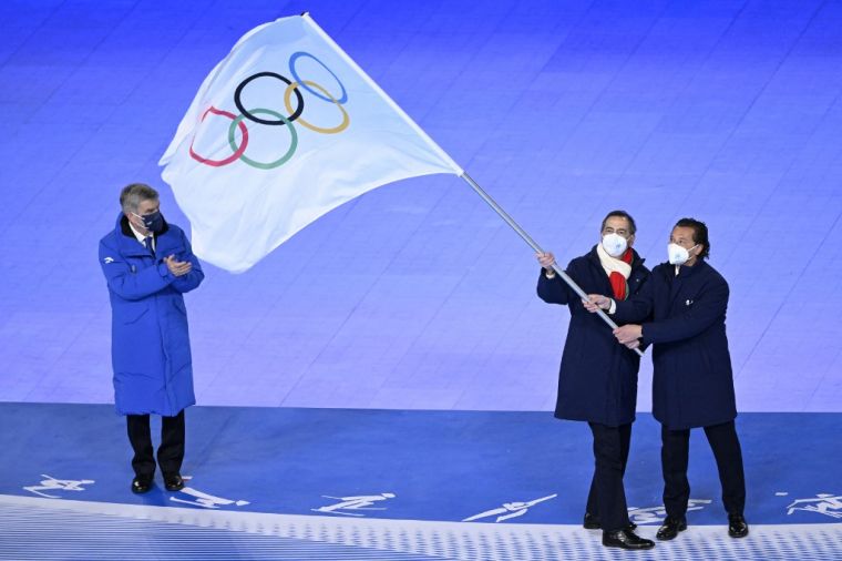 奧會主席巴赫（左）監督下，義大利兩位市長接會旗，2026年接辦冬奧。（法新社）