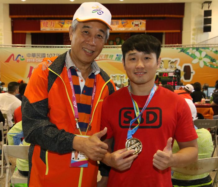 高雄市運發局代理局長周明鎮恭賀林逸鈞在健力男子59公斤級奪得金牌。高雄市運動發展局提供