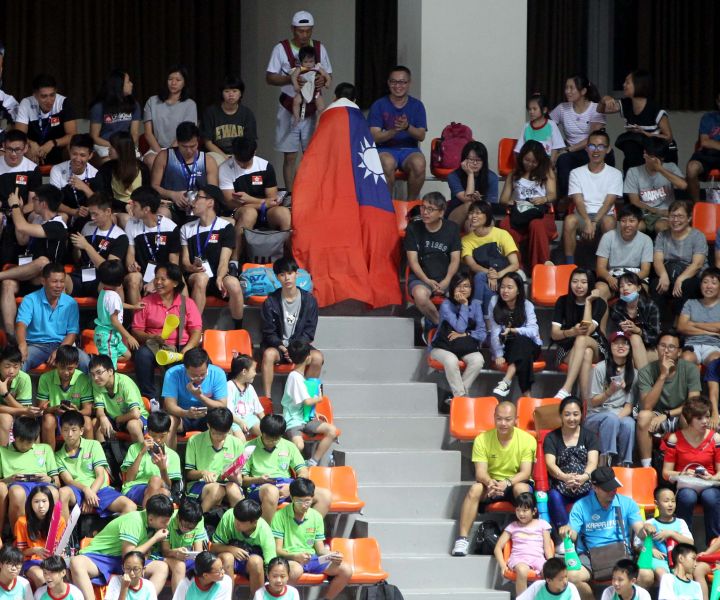 三民國小排球隊蔡鎮宇(披國旗者)跑完一圈，一旁觀眾給他拍拍手。林嘉欣／攝影。