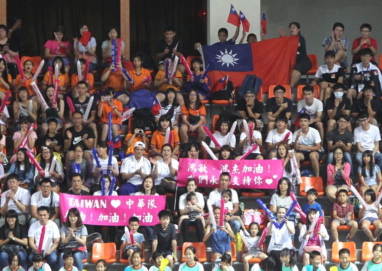 三民國小排球隊蔡鎮宇、蔡鎮謙和媽媽林馨蘋帶著大小國旗進場加油。林嘉欣／攝影。
