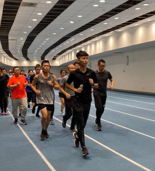邱韋翔（手持麥克風者）於高雄國家體育場分享跑步訓練經驗，也帶動民眾們熱情投入練習。高雄市政府運動發展局提供
