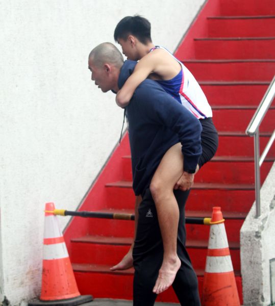 教練陳鴻傑把受傷的劉家成背到場邊。林嘉欣／攝影。