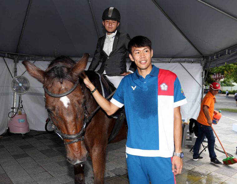 亞運男子110公尺跨欄銀牌陳奎儒(右)在馬術體驗區和馬匹互動。林嘉欣／攝影。