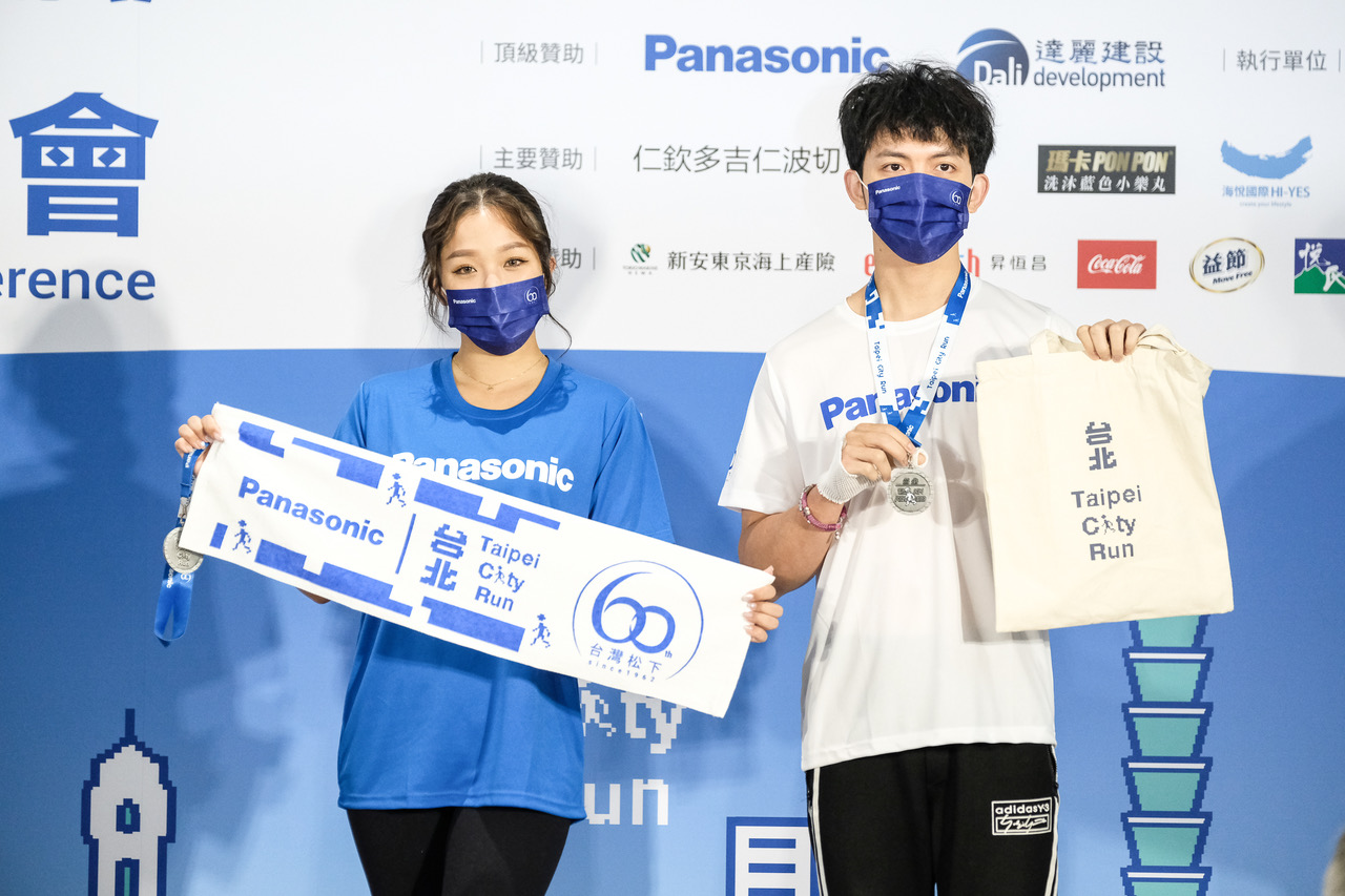 明日之星冠軍歌手賴慧如(左)郭忠祐展示2022 Panasonic台北城市路跑賽完賽毛巾和提袋 。大會提供