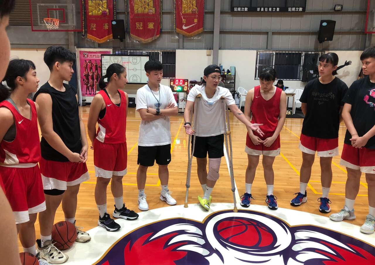 普門女籃總教練李宜瑄(中右)示範動作傷膝仍拄著拐杖精神講話。官方提供