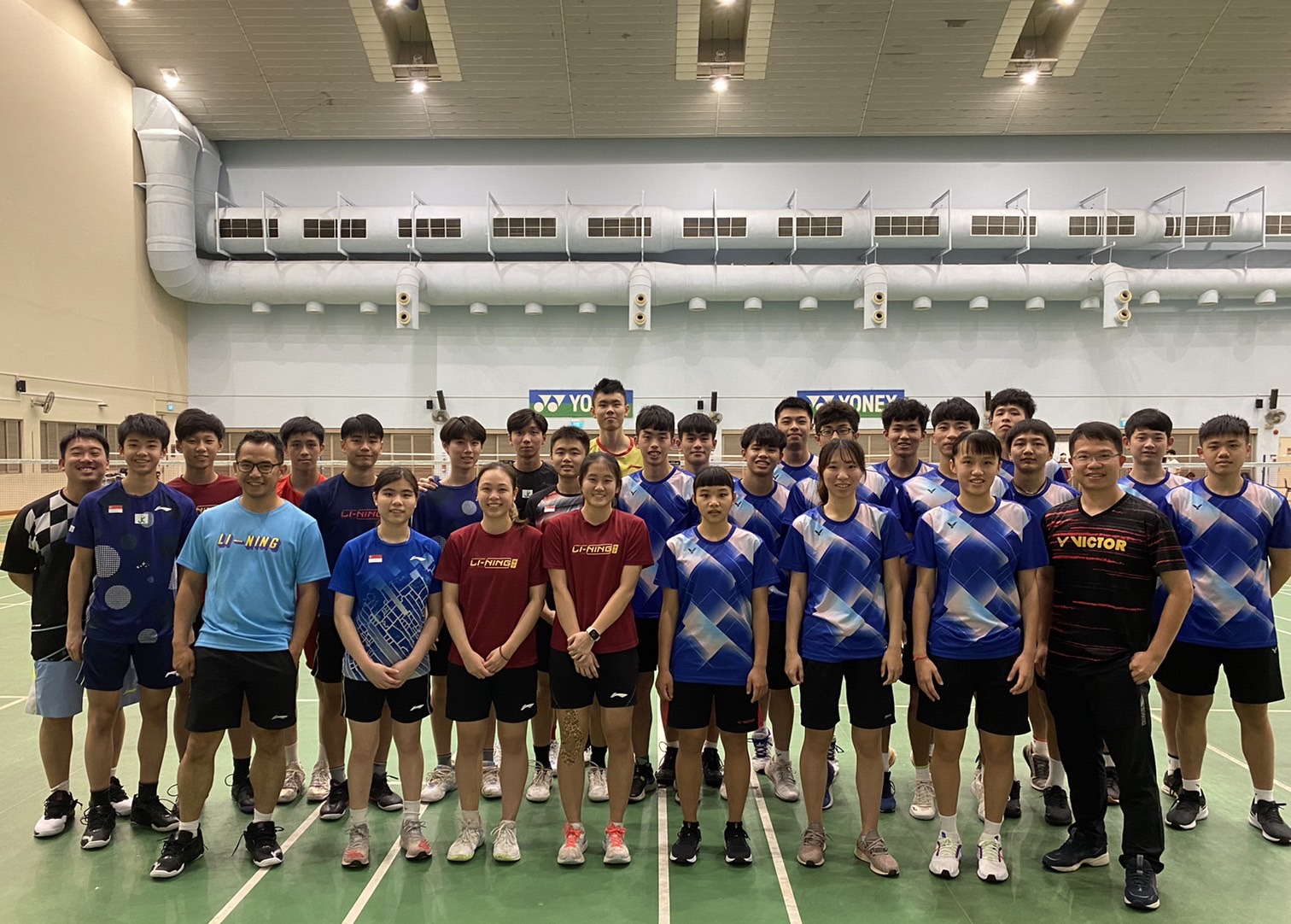 嘉義大學羽球隊與新加坡的教練和運動員在訓練場館合影。官方提供