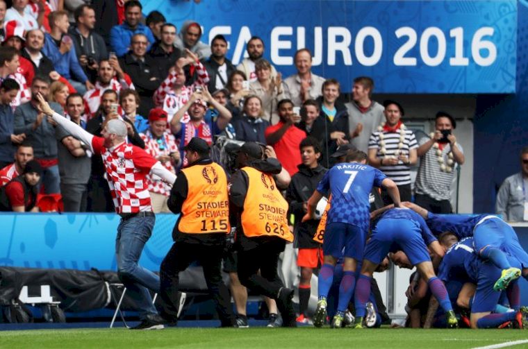 克羅埃西亞球迷衝進場內，法國保全人員要捉，一旁球員還在慶祝。(AFP)