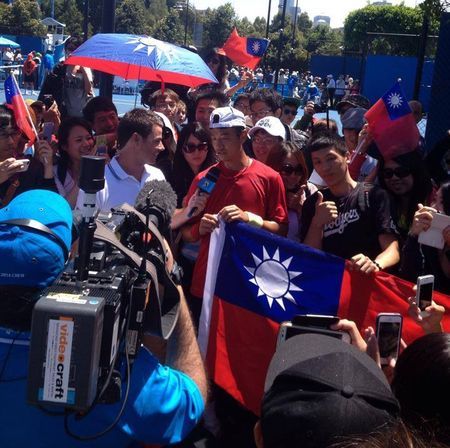 王宇佐在球場外拿著國旗接受採訪。（王宇佐提供）